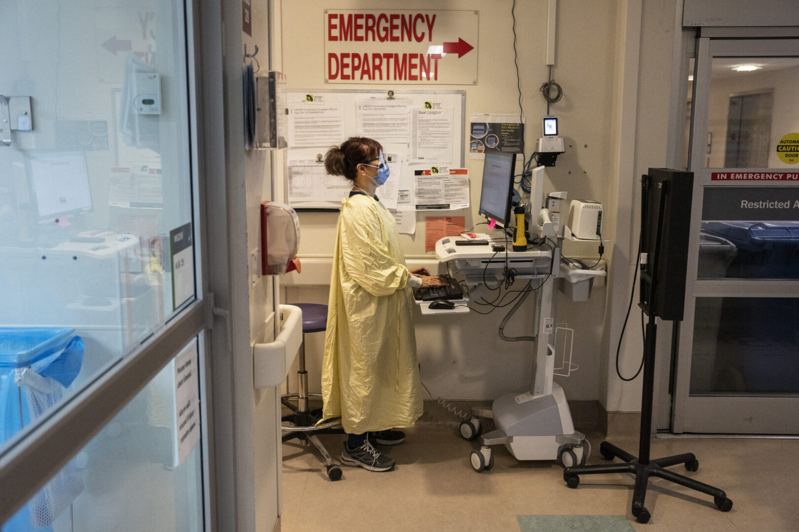 A person in yellow lab coat standing at a computer.