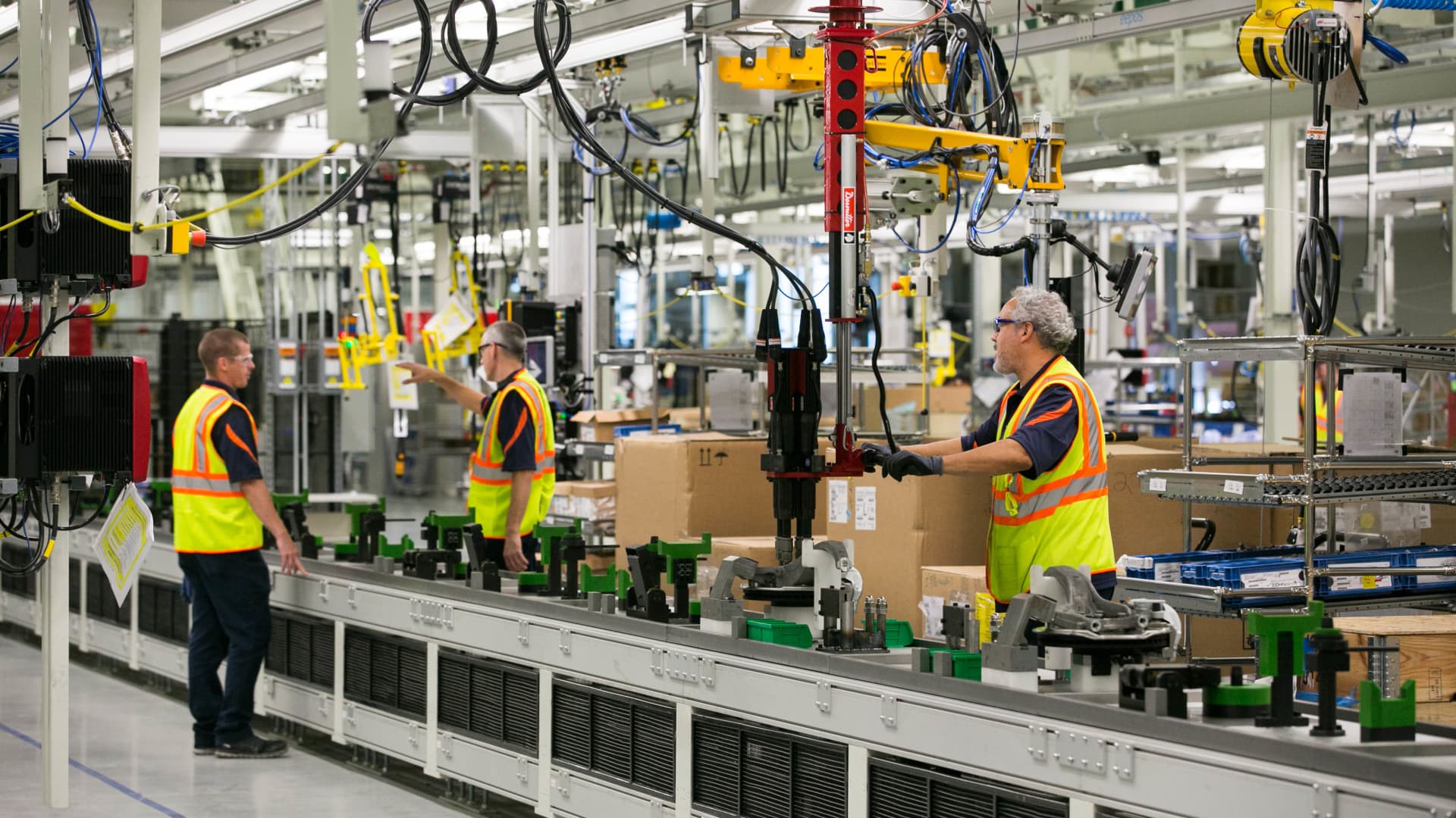 Two men working in a factory with boxes on the conveyor belt.