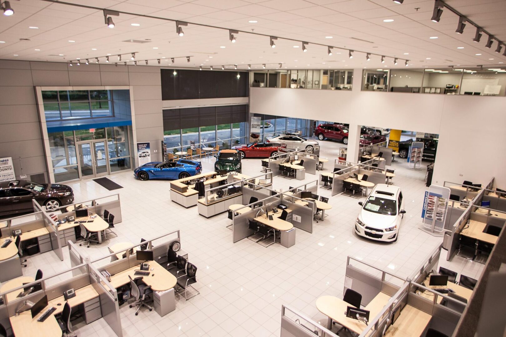 A car dealership with many desks and cars in it.
