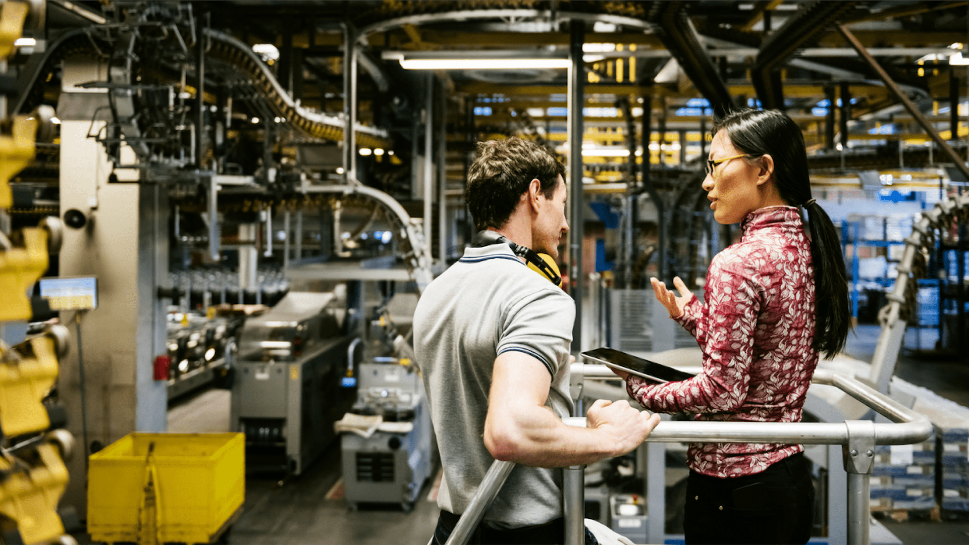 Two people talking in a factory setting.