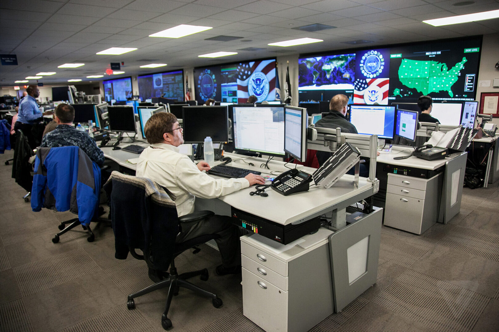 A man sitting at his desk in front of multiple monitors.
