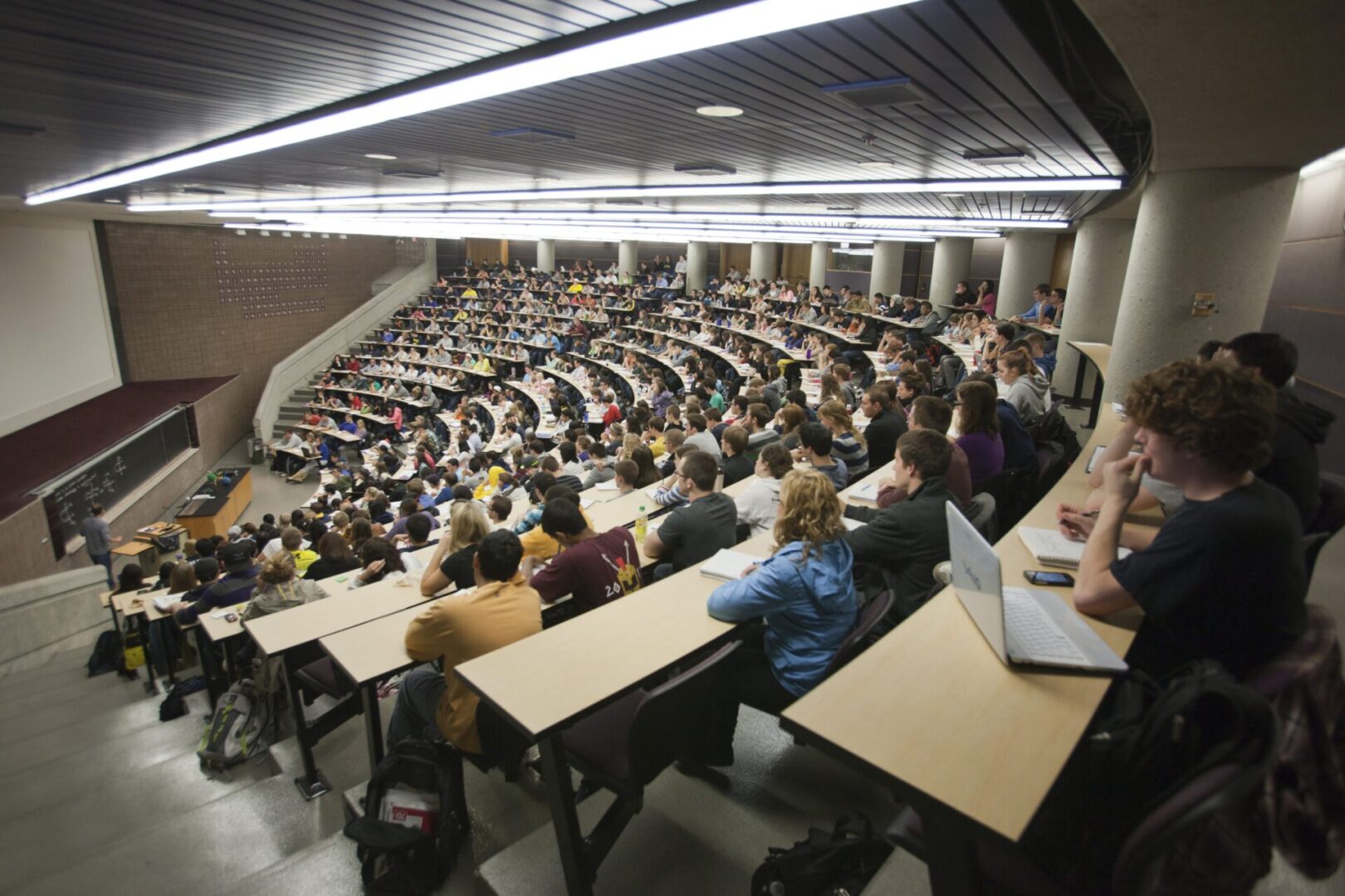 A large group of people sitting at tables in front of laptops.