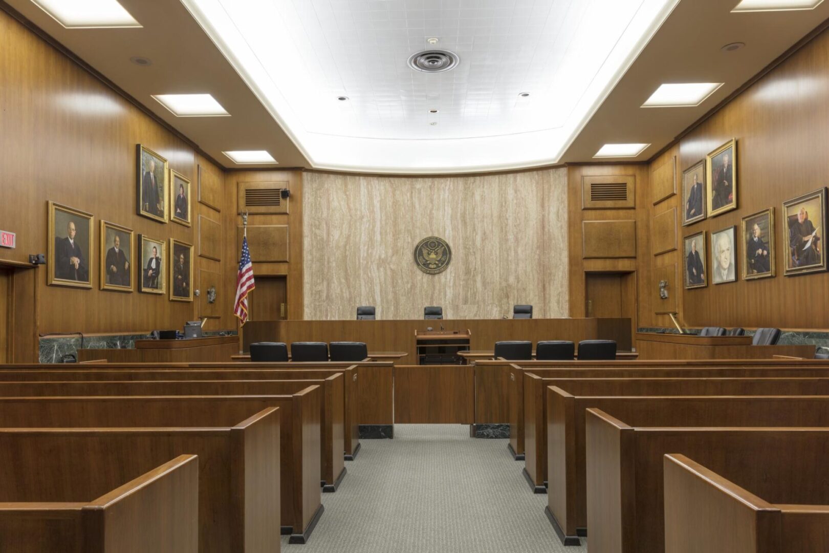 A courtroom with wooden benches and a flag on the wall.