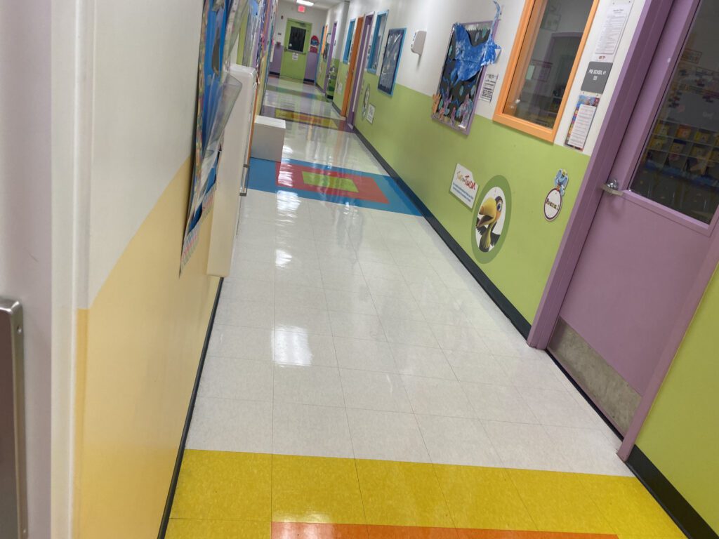 A hallway with yellow and green walls and a cartoon character on the wall.