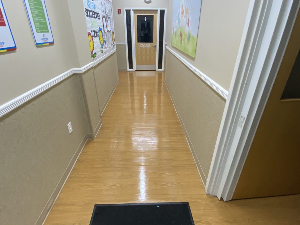 A hallway with a door way and a black mat.