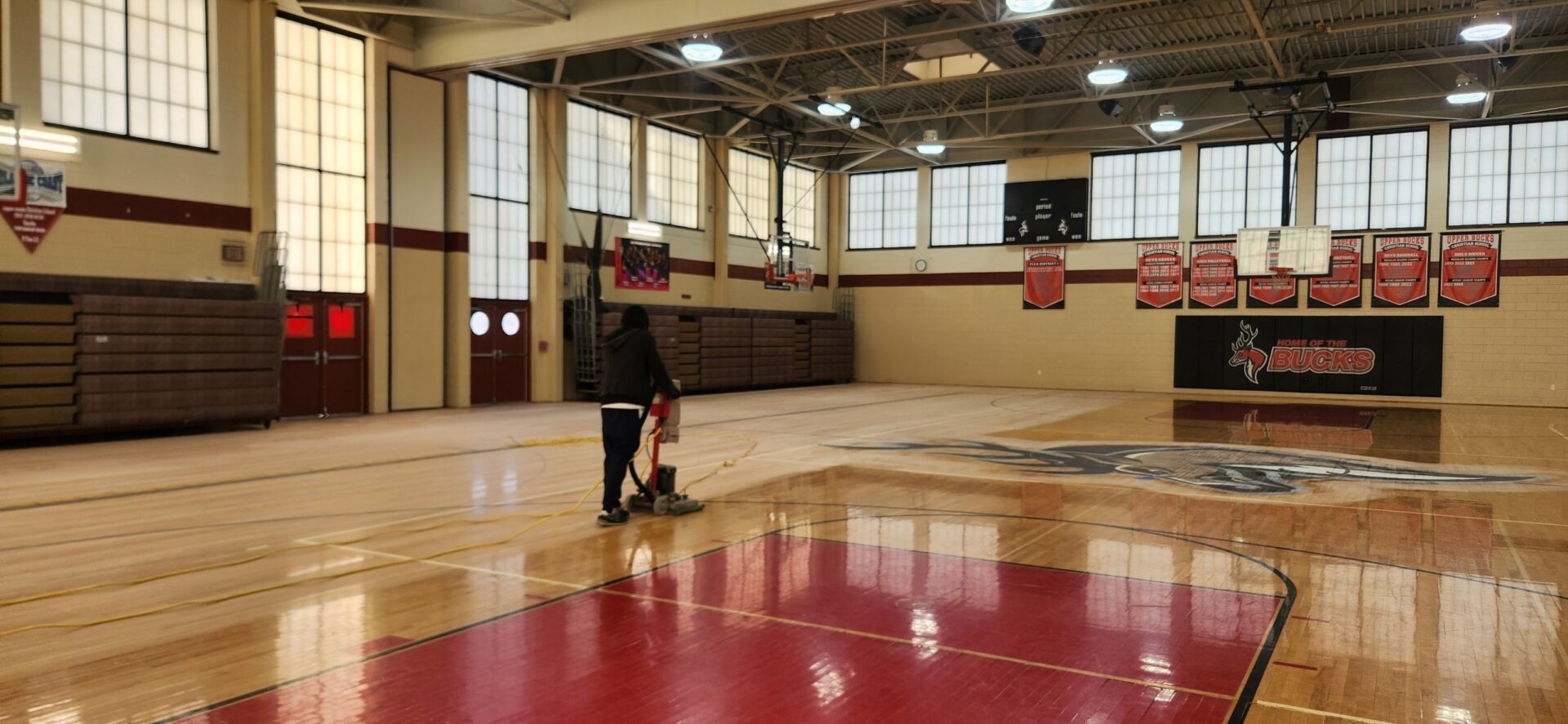 A person is standing in the middle of an indoor basketball court.