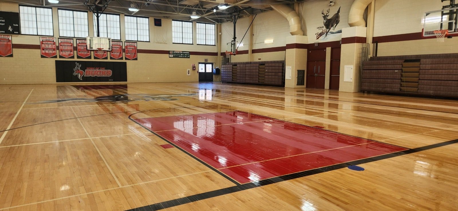 A gym with wooden floors and red mats.