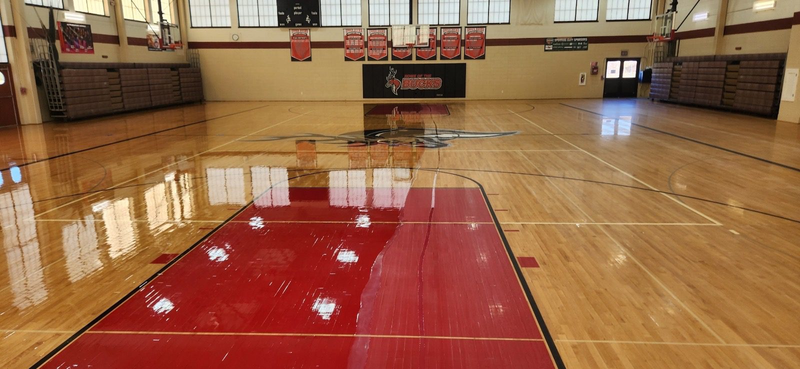 A gym with red floor and wooden seats.