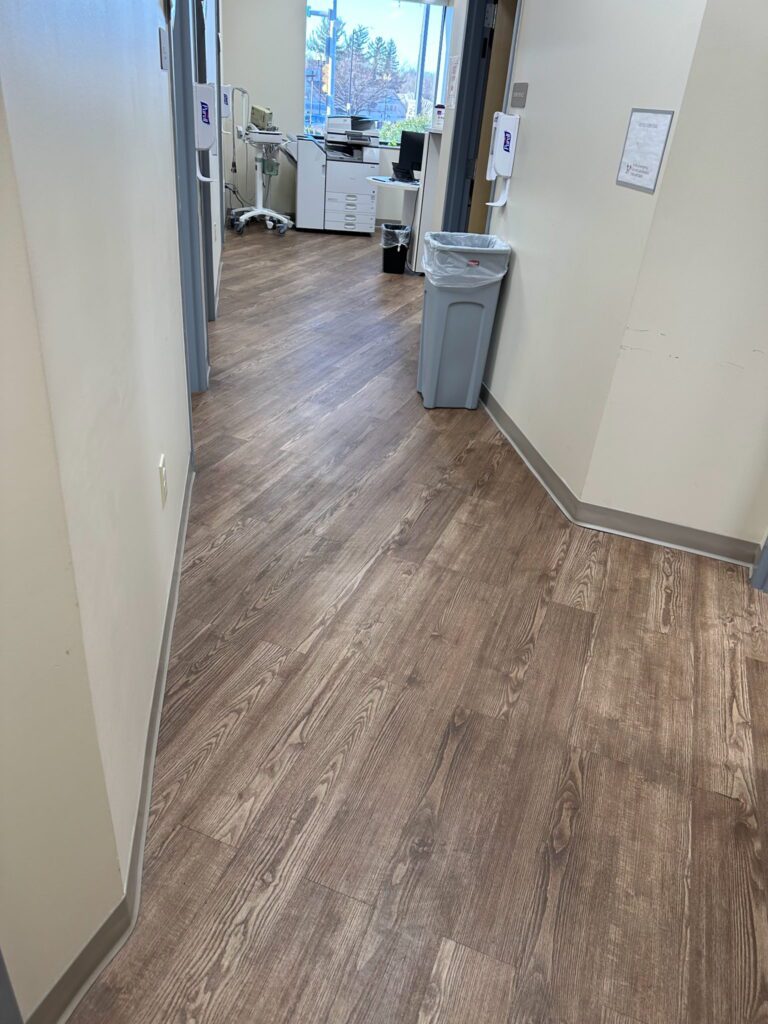 A hallway with wooden floors and white walls.