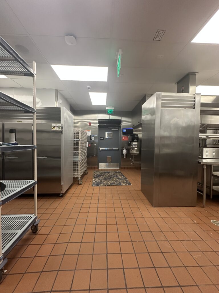 A kitchen with many stainless steel appliances and tiled floors.