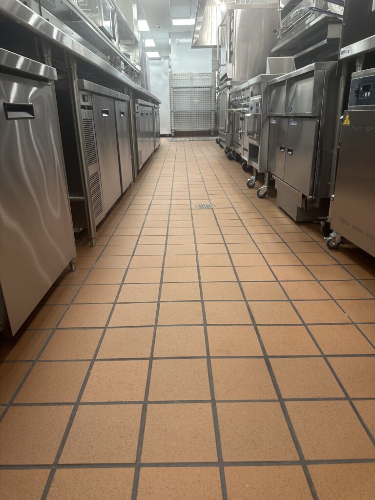 A kitchen with many stainless steel appliances and tiled floors.