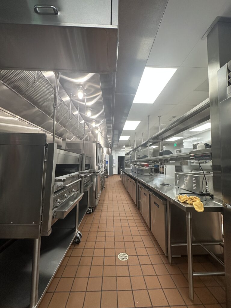 A kitchen with many stainless steel appliances and tiled floors.